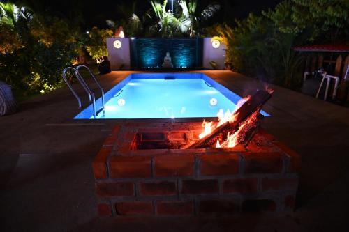 a swimming pool with a fire pit in a backyard at night at AVY Abode - 3bhk Farm Stay, Private Pool in Moinabad in Venkatāpur