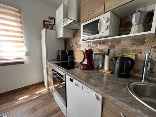 a kitchen with a white refrigerator and a sink at Apartmani Žak in Pridraga