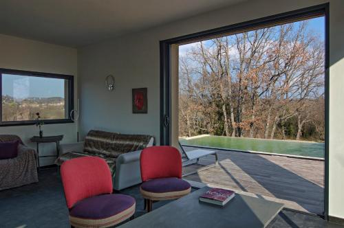 a living room with a couch and chairs and a large window at Le Mas Du Pont Roman in Mane