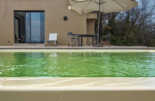 a swimming pool with a table and an umbrella at Le Mas Du Pont Roman in Mane