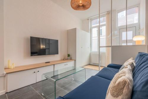 a living room with a blue couch and a tv at Maison 3 chambres, parking gratuit & proche métro in Croix