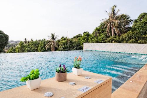 una piscina con dos macetas sentadas en una mesa de madera junto a una piscina en Happy Place Official, en Nai Yang Beach