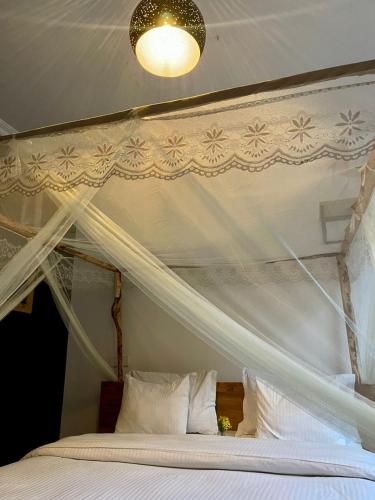 a bedroom with a canopy bed with white sheets and pillows at Eagle View Lodge - Kigali in Kigali