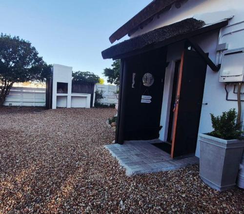 Una casa con una puerta negra y un patio de grava. en Charming 3 Bedroom Home in St Francis Bay, en Marina Glades