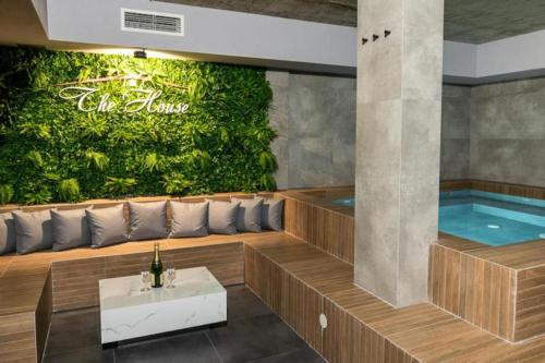 a wellness room with a pool and a green wall at "The House" Апартаменти и Термална зона in Velingrad