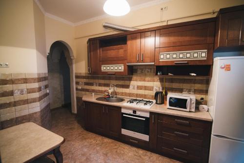 リヴィウにあるApartment on Bernarda Meretynaのキッチン(木製キャビネット、白い冷蔵庫付)