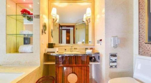 a bathroom with a sink and a toilet and a mirror at Fortune International Hotel in Xiawutun