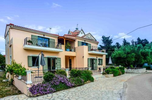 uma grande casa amarela com flores em frente em Maniata Holiday Apartments em Andipáta Erísou