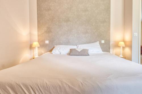 a bedroom with a large white bed with two lamps at La Chanconie in Chez le Turc
