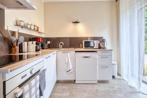 a kitchen with white appliances and a sink at La Chanconie in Chez le Turc