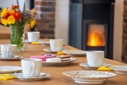 Una mesa de madera con tazas, platos y flores. en Traumraum Wittendorf, en Loßburg