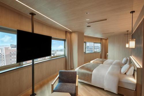 a bedroom with a bed and a flat screen tv at One Station Hotel Kumamoto -DLIGHT LIFE & HOTELS- in Kumamoto