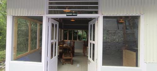 an open door of a building with a table and chairs at whistling woods resort in Kailāna