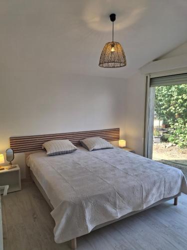 - une chambre avec un grand lit et une lampe pendant dans l'établissement Entre Terre et Mer, à Palau-del-Vidre