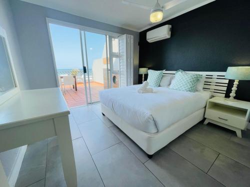 a bedroom with a white bed and a balcony at Beachy Seaside Serenity in Umdloti