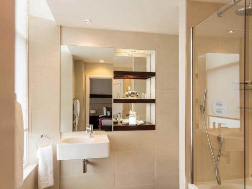 a bathroom with a sink and a shower and a mirror at Mercure Aberdeen Caledonian Hotel in Aberdeen