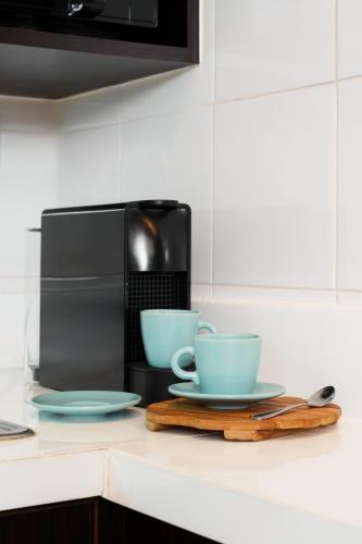two cups and saucers on a counter next to a microwave at Azure Dreams King Suite Retreat near BTS & Fast WiFi in Khlong Toei