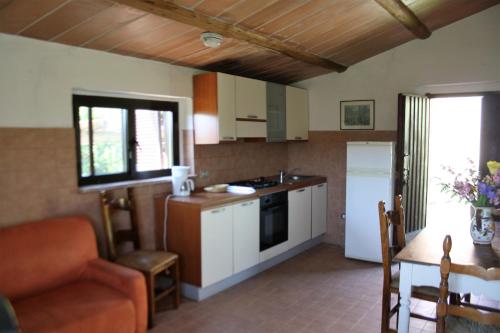 a kitchen with white cabinets and a table with a chair at Agriturismo Materno in Radicondoli