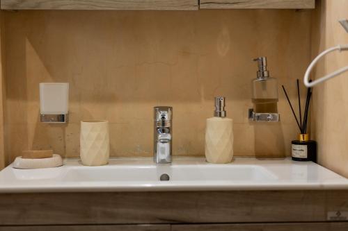 a bathroom sink with two cups and a faucet at My Nafpaktos Resort in Nafpaktos