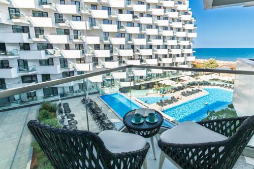 an apartment balcony with chairs and a swimming pool at Scorpios in Infinity Pool & Spa Resort in Mamaia Sat/Năvodari
