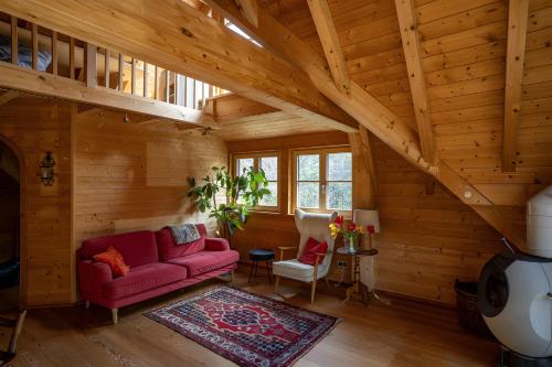 a living room with a red couch in a cabin at Ferienwohnung am Hirschenmoor in Breitnau