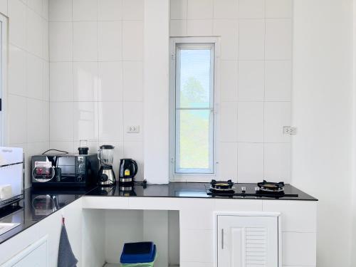 a white kitchen with a stove and a window at The Saeki House in Wok Tum