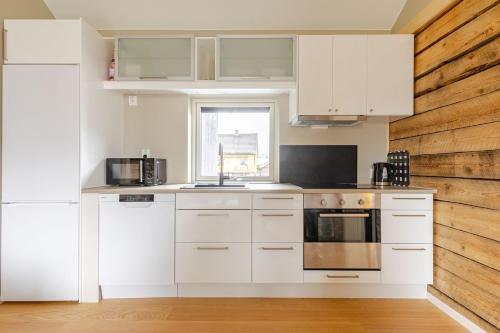 a kitchen with white cabinets and a wooden wall at Relaxing Stay close to Nature and History in Eidsvoll