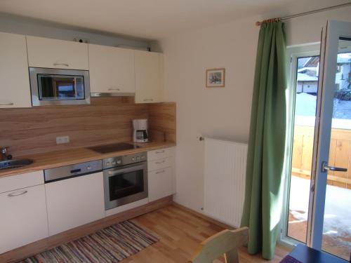 a kitchen with white cabinets and a sink and a microwave at Apartment Leber in Ehrwald