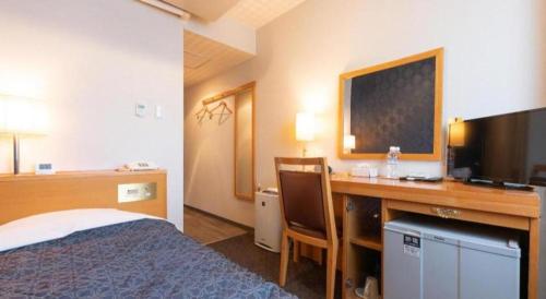 a hotel room with a bed and a desk at Tabist Sunshine Koga in Koga