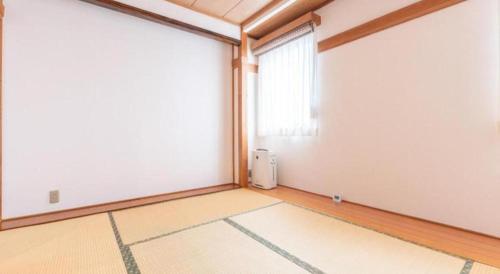 an empty room with a window and a white wall at Tabist Sunshine Koga in Koga