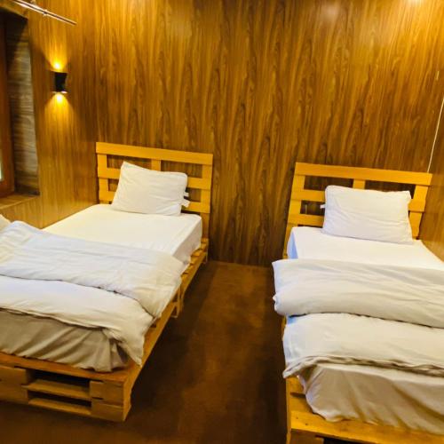 two beds in a room with wooden walls at Biafo Resort Skardu in Skardu