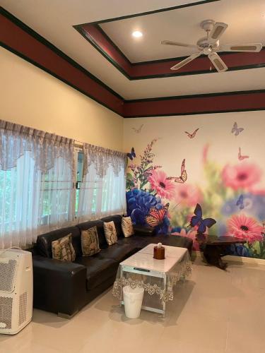 a living room with a black couch and a flower mural at Saiyok River House in Sai Yok
