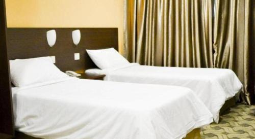 two beds in a hotel room with white sheets at YMCA Kuala Lumpur in Kuala Lumpur