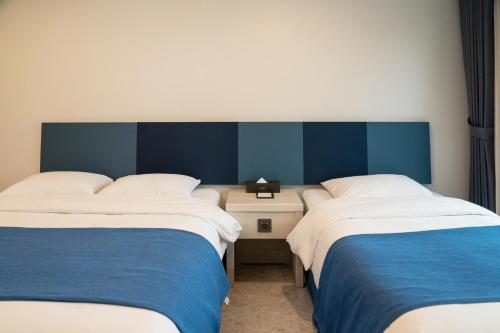 two beds in a room with blue and white at Hallim Resort in Jeju