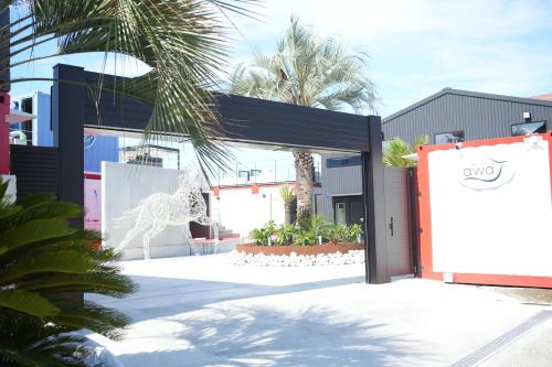 an entrance to a building with a sign and palm trees at awaJ Beach Club アワジェイビーチクラブ in Awaji