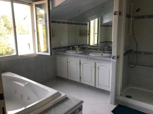 une salle de bain avec deux lavabos et une baignoire dans l'établissement Villa face mer, plage, à Saint-Georges-de-Didonne