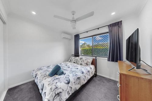 a bedroom with a bed and a flat screen tv at Pacific Pines 3BR Peaceful Home Stay in Gold Coast
