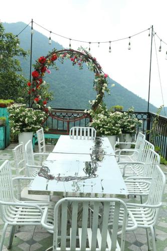 a table with white chairs and an arch with roses at Roses Homestay- Venuestay in Tam Ðảo
