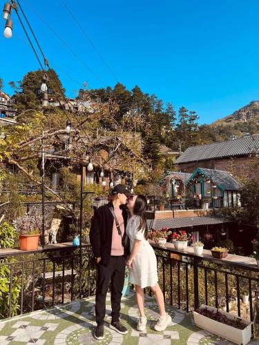 a man and a woman kissing in front of a garden at Roses Homestay- Venuestay in Tam Ðảo