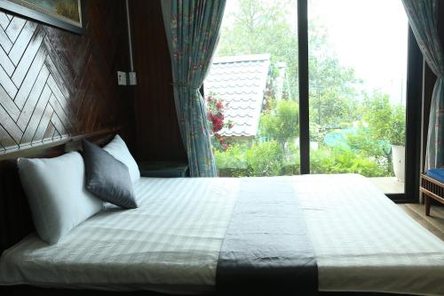 a bedroom with a bed and a large window at Roses Homestay- Venuestay in Tam Ðảo