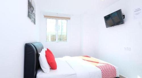 a white bedroom with a bed with red pillows at OYO 718 Mr J Hotel Wakaf Che Yeh 1 in Kota Bharu