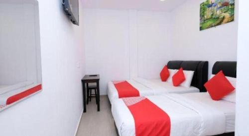 two beds in a white room with red pillows at OYO 718 Mr J Hotel Wakaf Che Yeh 1 in Kota Bharu