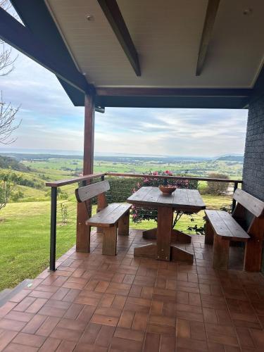 a table and two benches on a patio with a view at Ocean Willow Gerringong in Gerringong