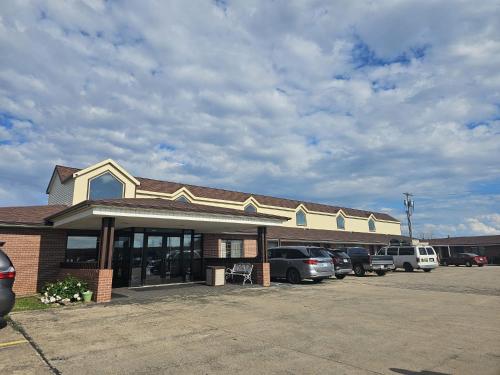 a building with cars parked in a parking lot at Capital O Marysville Surf Motel Kansas in Marysville