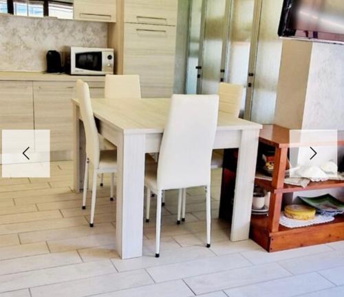 a dining room table with white chairs in a kitchen at La Terrazza in Albissola Marina