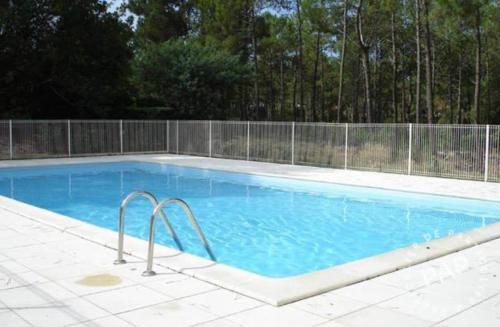 une grande piscine bleue avec une clôture dans l'établissement Maison au calme dans le golf de Lacanau, à Lacanau