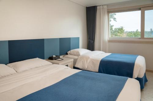 a hotel room with two beds and a window at Hallim Resort in Jeju