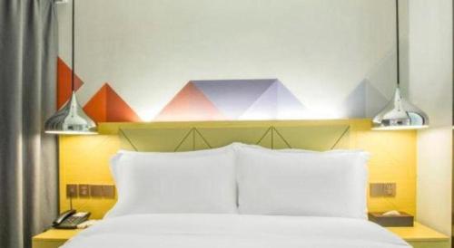 a bedroom with a bed with two lights above it at Borrman Hotel Zhuhai Gongbei Port Fuhuali Light Rail in Zhuhai