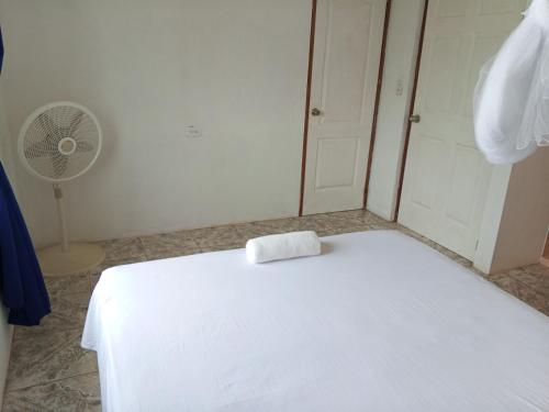 a white bed in a room with a fan at Christina's Guest House OFFICIAL in Little Corn Island