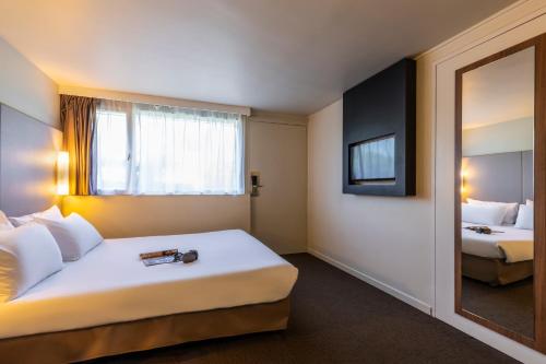 a hotel room with a large bed and a mirror at Campanile Pontarlier in Pontarlier